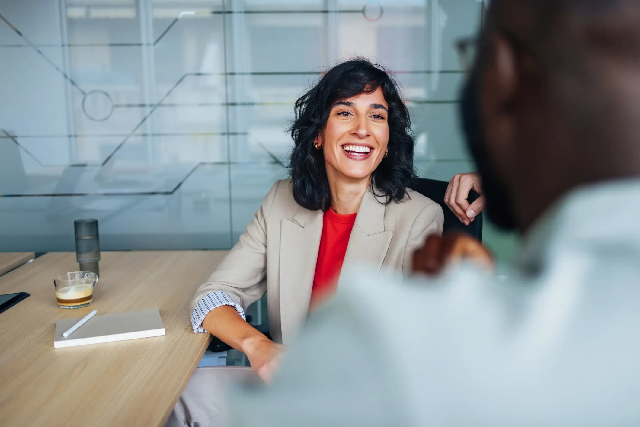 Lächelnde Frau In Einem Geschäftstreffen, Das Sich Mit Einem Kollegen Am Bürotisch Auseinandersetzt